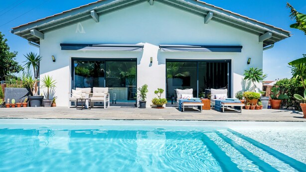A modern house with a swimming pool, large windows, and outdoor seating.