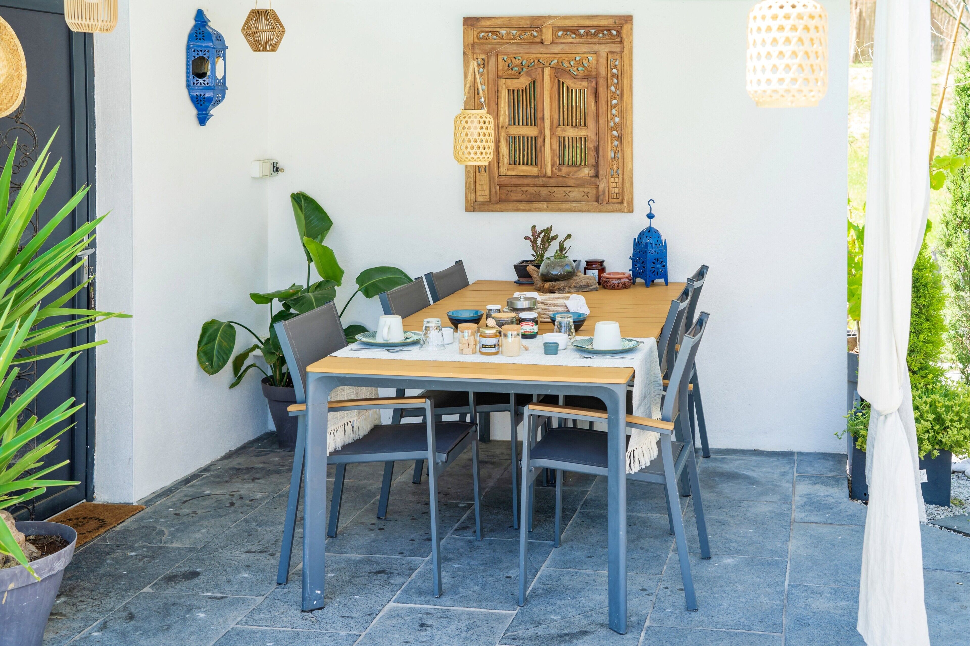 Een eetruimte met een houten tafel, stoelen en potplanten.