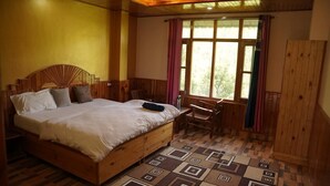 A wooden bedroom with a bed, a desk, and a window with curtains. - Applewood Heaven (Bhuntar)