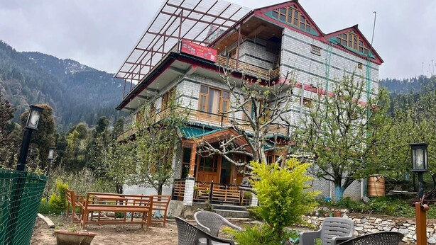 A two-story building with a balcony, outdoor seating, and a view of the mountains. - Applewood Heaven (Bhuntar)