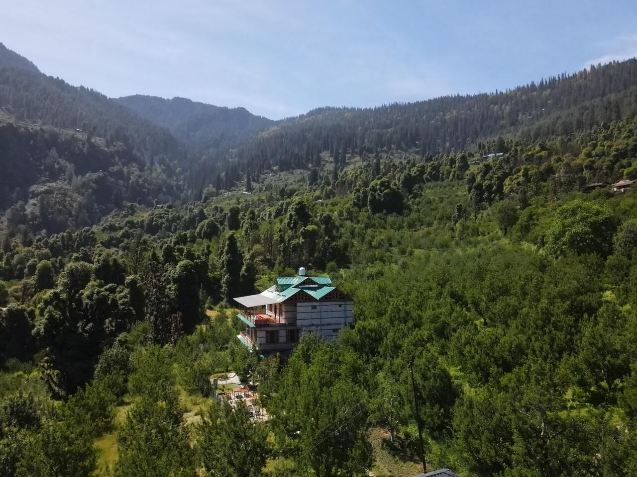 A house surrounded by dense forest and hills.