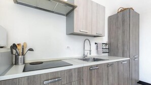 A modern kitchen with a built-in stove, a sink, and wooden cabinets. - Hostdomus - Esther House (Noli)