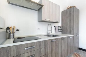 A modern kitchen with a built-in stove, a sink, and wooden cabinets. - Hostdomus - Esther House (Noli)