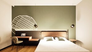 Quarto de hotel moderno com uma cama, uma escrivaninha e uma cadeira.