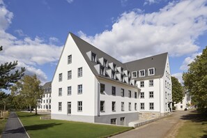 A modern multi-story building with a symmetrical facade, large windows, and a sloped roof. - Essential by Dorint Mannheim Taylor Park (Mannheim)