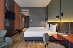 A modern hotel room with a large bed, a desk, a chair, and a television. - Essential by Dorint Mannheim Taylor Park (Mannheim)
