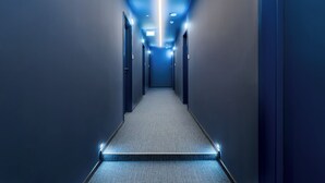 A narrow, well-lit hallway with a carpeted floor and doors on both sides. - LOCA by Ambiente Apartments (Bratislava)