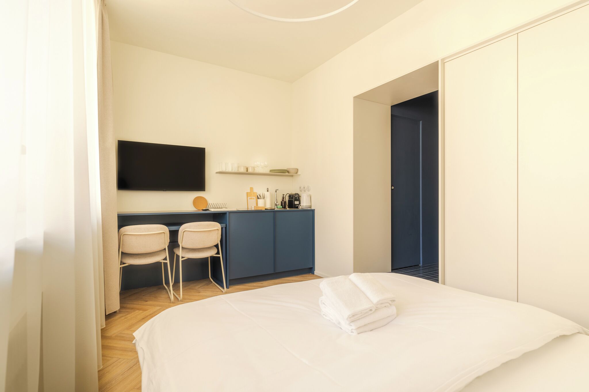 Une chambre d’hôtel comprenant un lit, un bureau avec des chaises, un téléviseur à écran plat et une armoire.