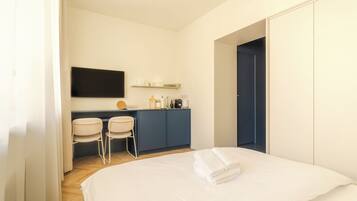 Une chambre d’hôtel comprenant un lit, un bureau avec des chaises, un téléviseur à écran plat et une armoire.