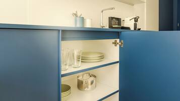 A kitchen with blue cabinets, a coffee maker, and a kettle on the countertop.