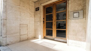 A building entrance with a wooden door, a sign above it, and a utility box on the wall. - LOCA by Ambiente Apartments (Bratislava)