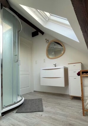 A room with a skylight, a glass shower enclosure, a white vanity, and a wooden ladder. - Appartement Cozy et design, position centrale, complètement équipé. (Perwez)