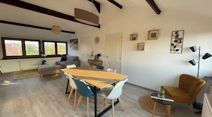 A spacious living area with a wooden dining table, blue and white chairs, a sofa, and a small side table. - Appartement Cozy et design, position centrale, complètement équipé. (Perwez)
