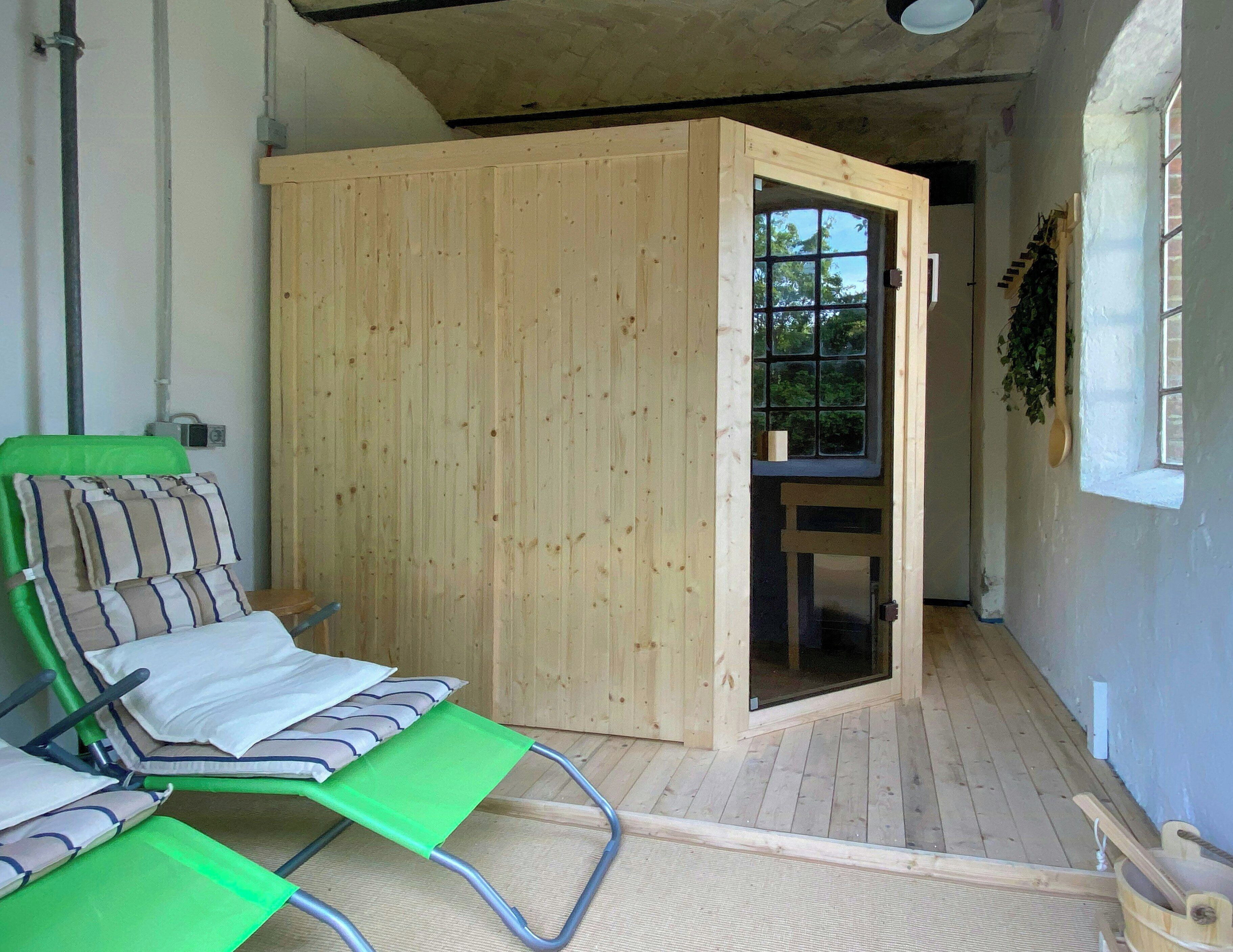 A room with a wooden door, a green chair, and a small table.