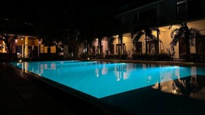 A swimming pool at night with reflections, surrounded by buildings and palm trees. - The Reef Resort Nilaveli - Trincomalee (Nilaveli)