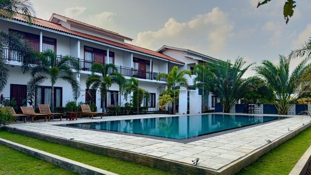 A two-story building with a swimming pool, palm trees, and a well-maintained lawn. - The Reef Resort Nilaveli - Trincomalee (Nilaveli)