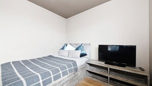 Ein Schlafzimmer mit einem Bett, einem Fernseher und einer hölzernen Bank.