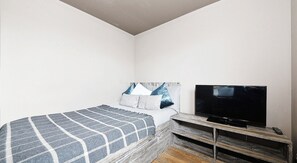 A bedroom with a bed, a TV, and a wooden bench. - Student Only Marketgait (Dundee)