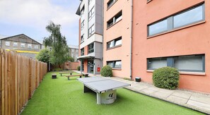 A courtyard with artificial grass, a ping pong table, benches, and a wooden fence. - Student Only Marketgait (Dundee)