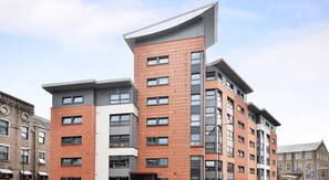 A modern multi-story building with a mix of brick and concrete facades, large windows, and a unique cantilevered section. - Student Only Marketgait (Dundee)