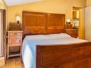 A bedroom with a wooden bed, a nightstand, a dresser, and a mirror.