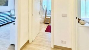 A hallway with a bed, a painting, and a window.