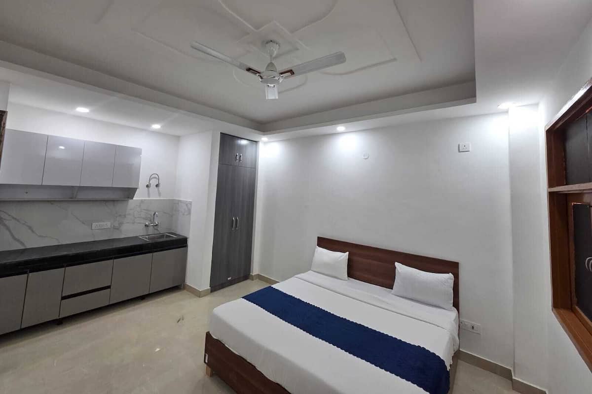 A bedroom with a bed, a ceiling fan, a built-in wardrobe, and a kitchen area with cabinets and a countertop.