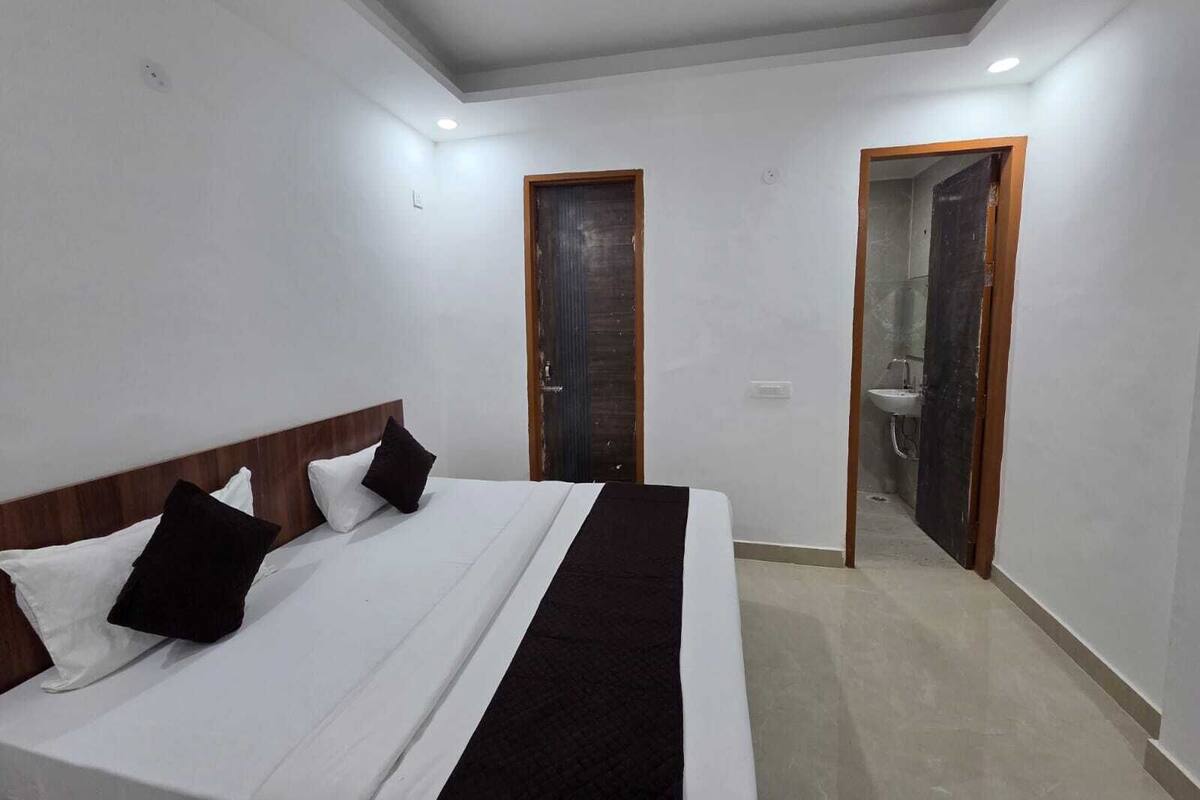 A bedroom with a bed, a wooden headboard, a black and white striped blanket, and a door leading to a bathroom.