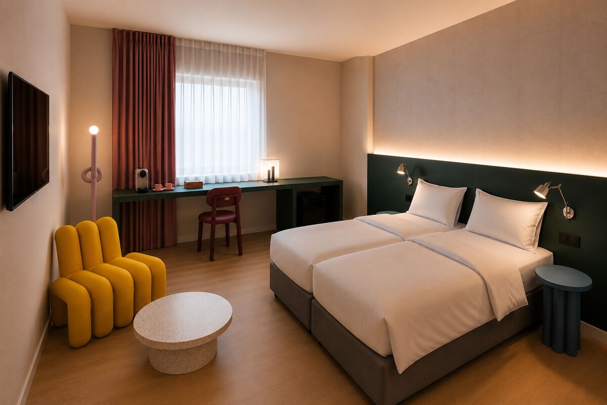 Habitación de hotel con cama, escritorio, silla, una mesita redonda y televisor.