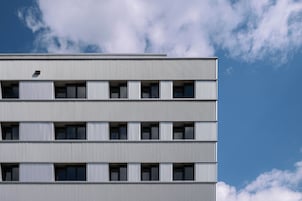Um edifício de vários andares com design arquitetônico moderno, apresentando uma série de varandas e janelas.