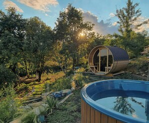 Eine zylindrische Holzkonstruktion mit Glastür, Holzterrasse und Schwimmbecken.