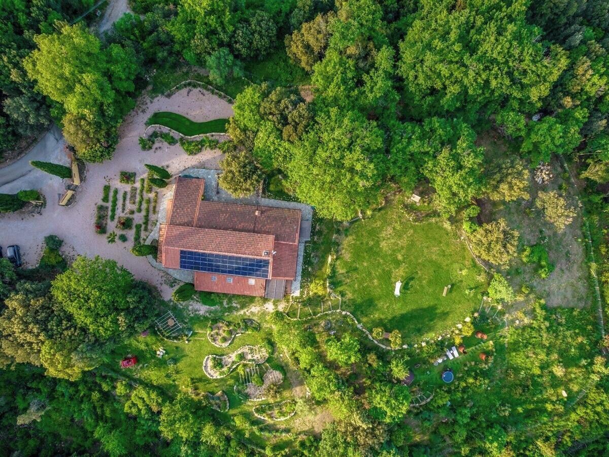 An aerial view of a building with a red roof, surrounded by lush greenery and a well-maintained garden.