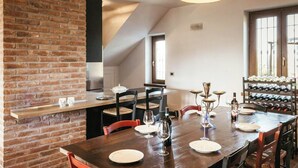 A dining area with a brick wall, wooden table, chairs, wine glasses, and a wine rack.