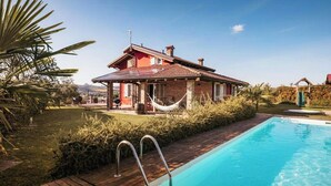 A house with a swimming pool, a hammock, and a garden.