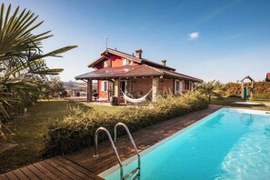 Una casa con piscina, un'amaca e un giardino.