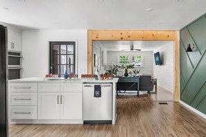 Una cocina moderna con armarios blancos, lavavajillas y techo de madera.