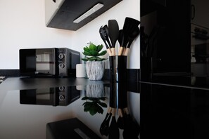 A modern kitchen with a black countertop, a microwave, a plant, and kitchen utensils.