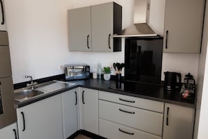 A modern kitchen with a built-in oven, a microwave, a kettle, and a coffee maker.