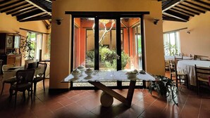 Un comedor con una mesa dispuesta para dos personas, una vista a través de un vano y una cocina visible al fondo.