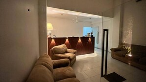 A modern living room with a sofa, a reception desk, and a glass partition. - NN Beach Resort Nilaveli (Trincomalee)