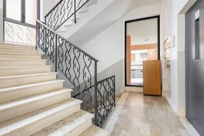 Eine Treppe mit Metallgeländer, einer Holztür und Blick in einen Raum mit Holzboden.