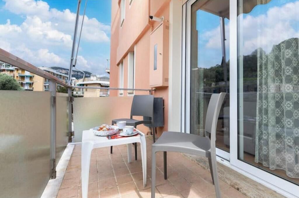 Uma varanda com mesa posta para dois, uma cadeira e vista para a cidade.