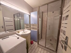 Ein Badezimmer mit Duschkabine, Waschbecken und Spiegel.