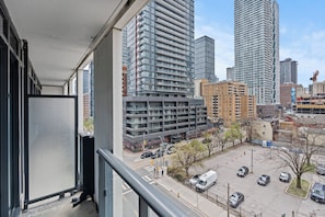 Un immeuble de grande hauteur offrant une vue sur le paysage urbain, avec d’autres bâtiments imposants et un parking rempli de voitures.
