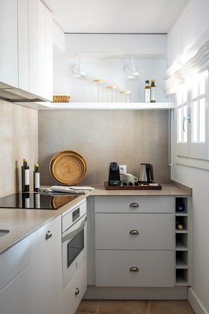 Eine kompakte Küche mit modernem Design, inklusive Einbauofen, einer Kaffeestation und einer kleinen Ablagefläche.