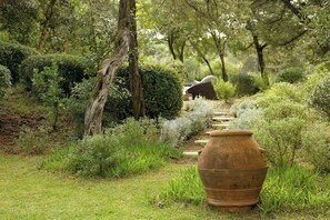 Ein Garten mit einem großen Blumentopf, einem Weg und verschiedenen Pflanzen.