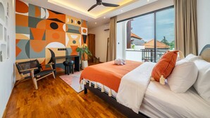 A modern hotel room with a large bed, a desk, a chair, a ceiling fan, and a large window offering a view of the outside. - Alisa 3 Villa (Kerobokan)