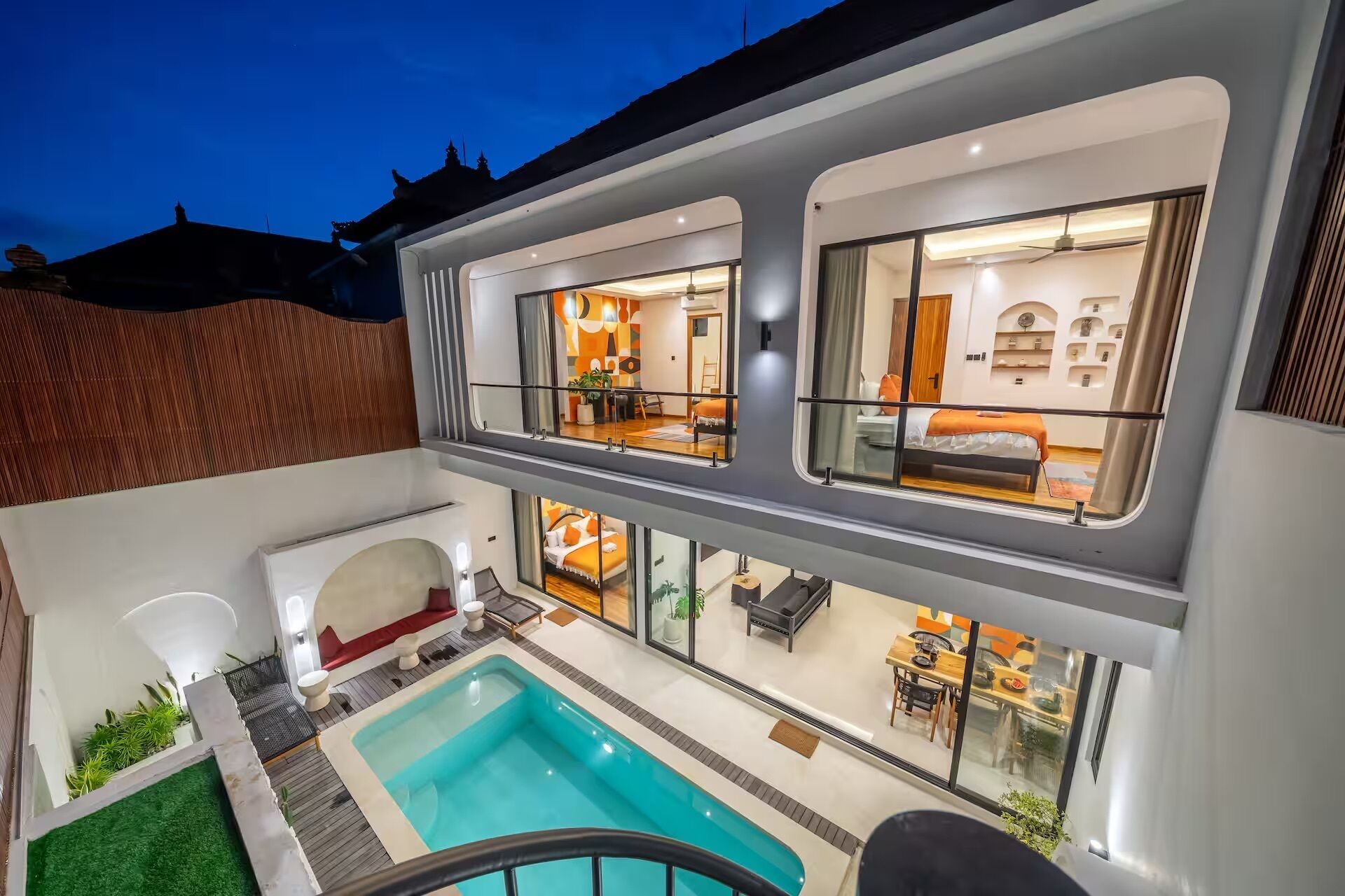 Ein modernes, zweistöckiges Gebäude mit Swimmingpool, mehreren Zimmern mit großen Fenstern und einem Balkon.