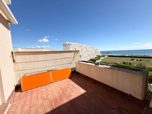 Eine Dachterrasse mit Blick auf das Meer, einem Backsteinboden und einer beigen Wand.
