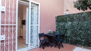 A patio with a table and chairs, a decorative gate, and a green wall.